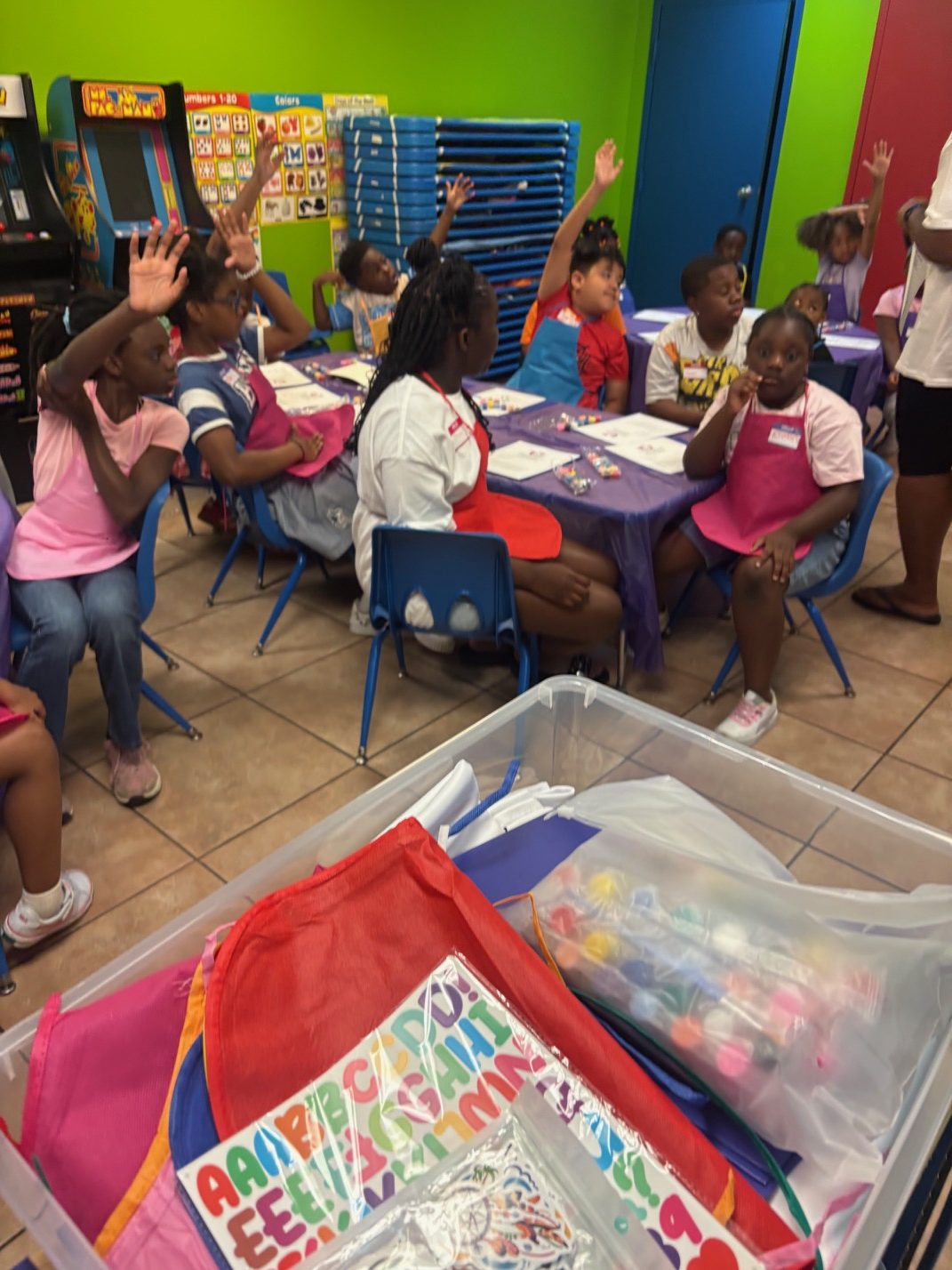 Children raise their hands during a Unique Little Savers class