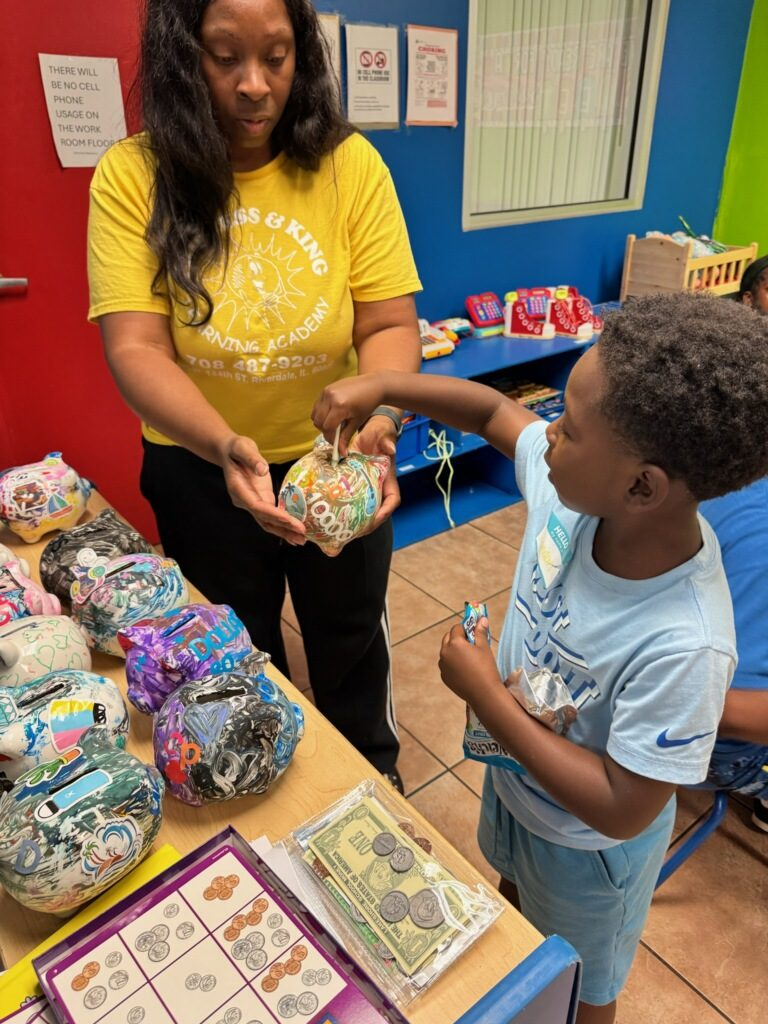 A young saver adds money to his decorated piggy bank